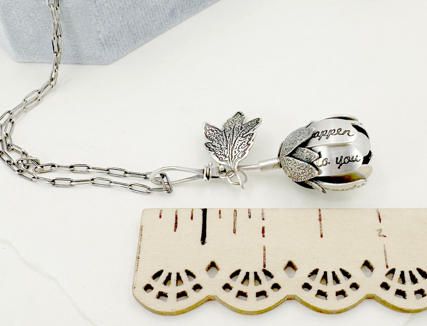 "Let everything happen..." kinetic flower with Rilke quote in sterling silver with black opal.