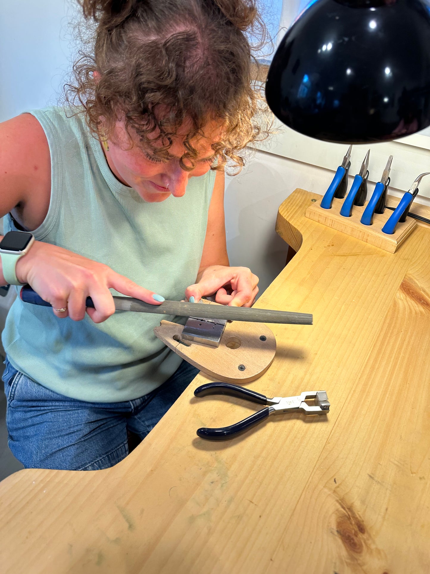 Person using a tool on a wooden surface with tools hanging on the wall.