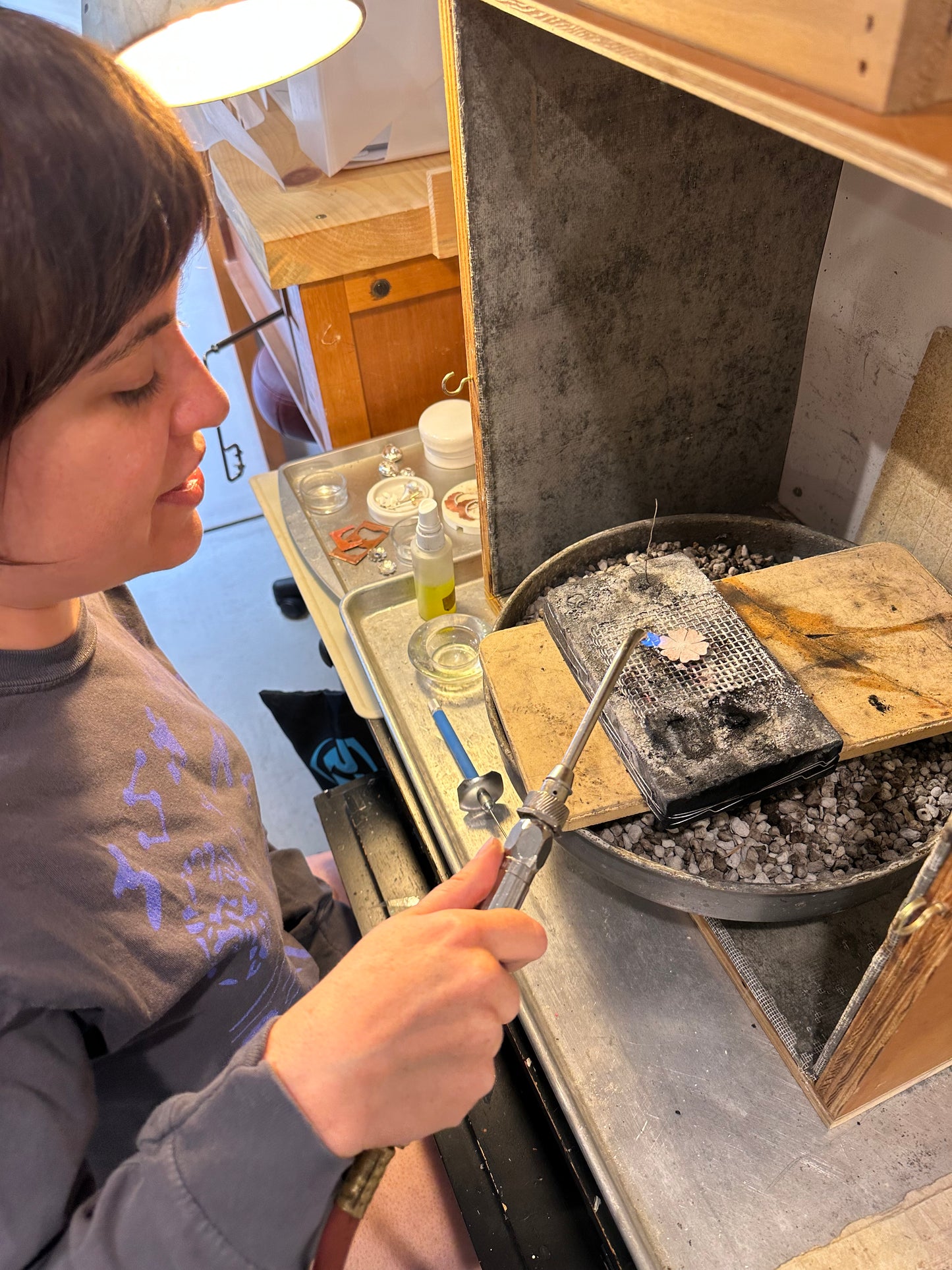 Person using a tool on a workbench with various items around
